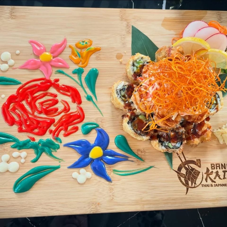 Fried sushi rolls with shredded carrots and lemon on a wooden board with colorful sauce art.