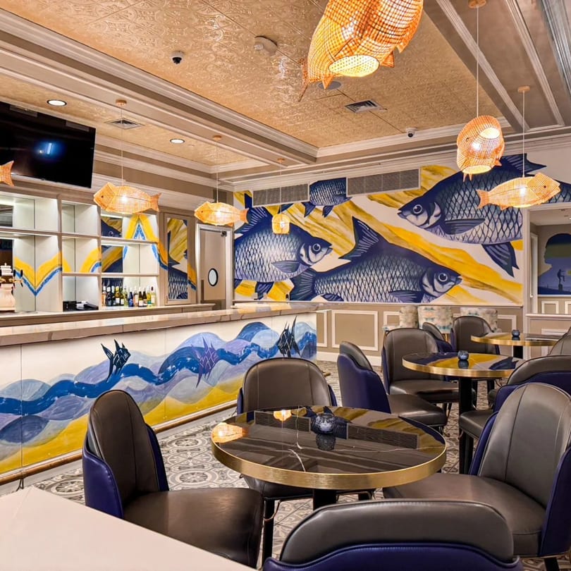 Interior of Bangkok Kaizen restaurant with fish murals, fish-shaped lights, and blue and gold decor.