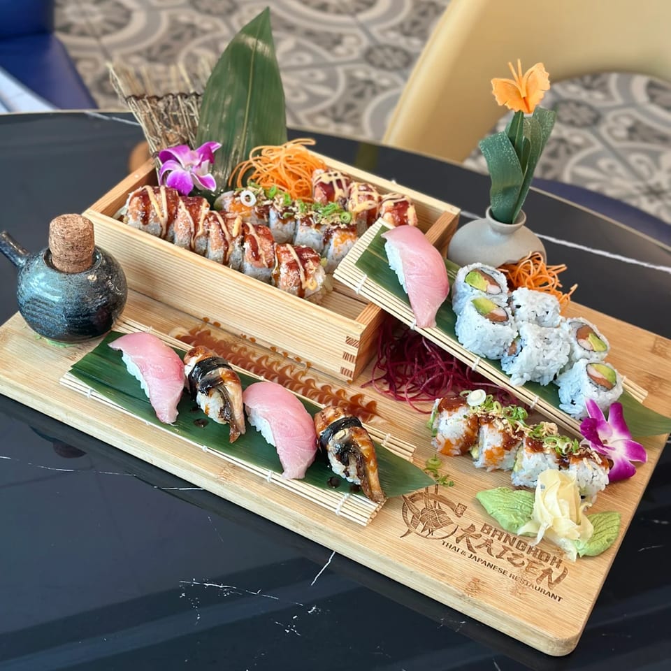 Assorted sushi and sashimi platter from Bangkok Kaizen, including nigiri, rolls, and a wooden serving tray.